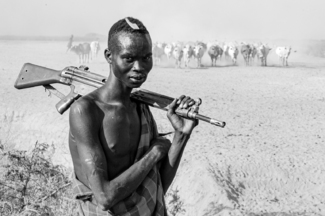 An Ethiopian pastoralist defends his herd as it heads to the