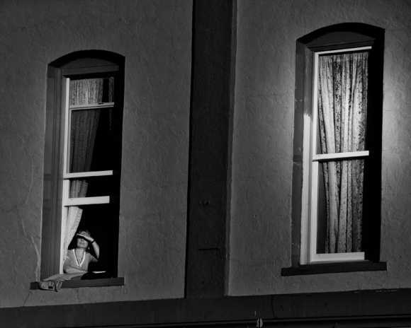 Woman looks out at Street from Window